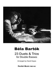 A black and white photo of Béla Bartók at a desk, looking intently at papers with a magnifying glass. Below the image, the following text is present: Béla Bartók 23 Duets & Trios for Double Basses Arranged by David Heyes. Recital Music RMD1092