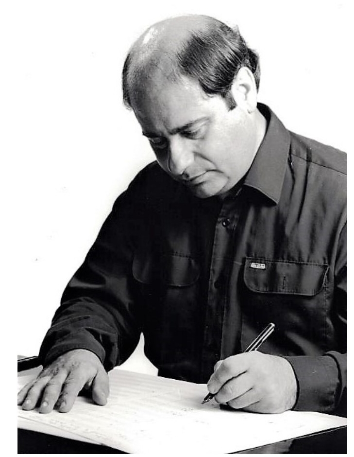 Black and white photo of composer Tony Osborne writing at his desk. He seems to be left-handed.
