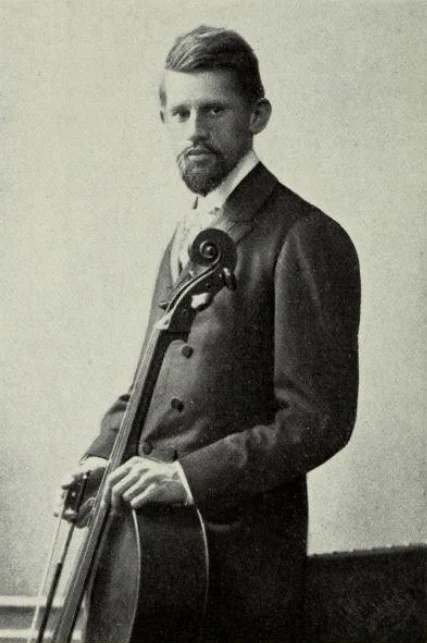 Black and white image of composer Hugo Schlemuller holding a cello