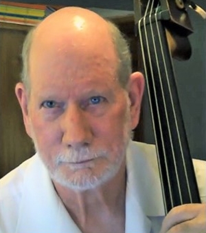 Photographic image of composer Michael Montgomery holding the neck or a double bass