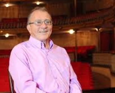Photograph of composer Federico Ruiz in a concert hall, wearing a pink shirt.