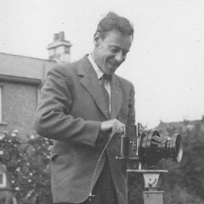 Black and white photograph of composer T.M. Lawrence with what looks like a hand cranked camera.