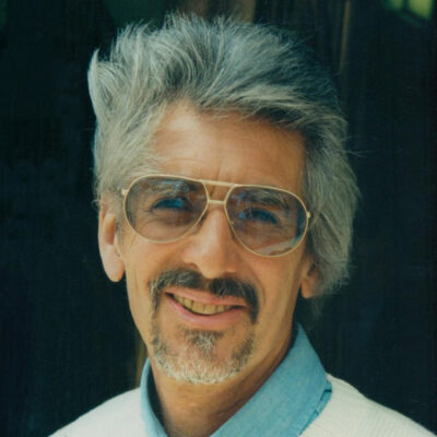 Photograph of British composer Lauries Holloway waering a light blue shirt and white jumper